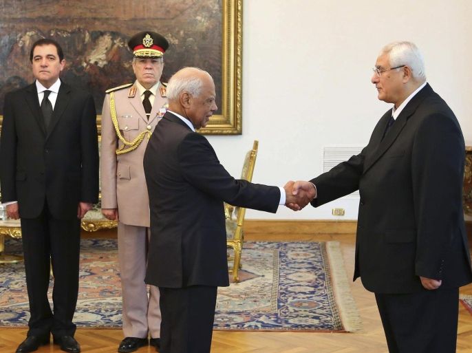 FILE - This file photo released by the Egyptian Presidency on Tuesday, July 16, 2013 shows interim President Adly Mansour, right, shaking hands with Prime Minister Hazem el-Biblawi during a swearing-in ceremony for new cabinet ministers at the presidential palace in Cairo, Egypt. Egypt’s interim prime minister Hazem el-Beblawi announced Monday the resignation of his Cabinet, a surprise move that could be designed in part to pave the way for the nation’s military chief to leave his defense minister’s post to run for president. El-Beblawi has often been derided in the media for his perceived indecisiveness and inability to introduce effective remedies to the country’s economic woes. (AP Photo/Egyptian Presidency, File)