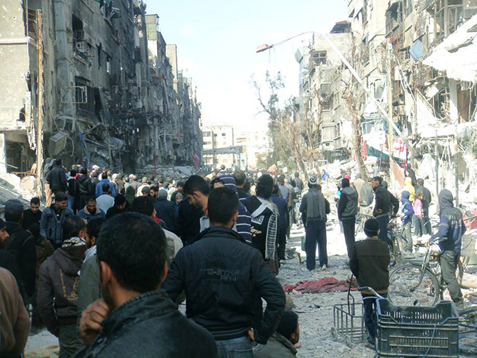المئات من سكان مخيم اليرموك في انتظار توزيع المساعدات الغذائية (الجزيرة نت)
