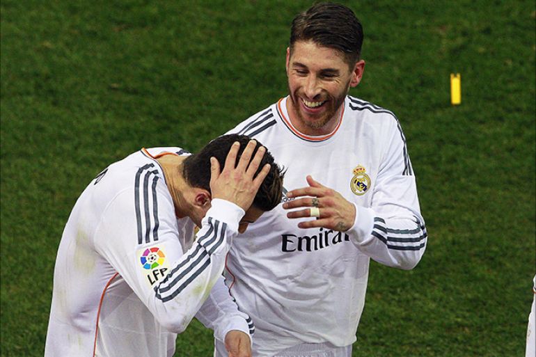 epa04070598 Real Madrid's Portuguese striker Cristiano Ronaldo (L) holds his head after he was hit by a yellow lighter next to his teammate Sergio Ramos (R) during the Spanish King's Cup semi final second leg soccer match between Atletico Madrid and Real Madrid at Vicente Calderon stadium in Madrid, Spain, 11 February 2014. EPA/BALLESTEROS