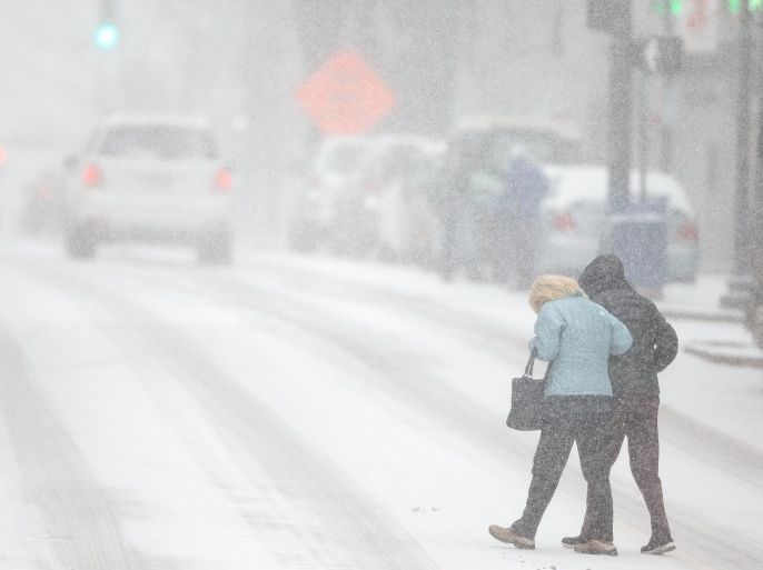 Pedestrians support each other as they cross S. Elm St. during a snow storm, Wednesday, Feb. 12, 2014 in Greensboro, N.C. As a third winter storm in as many days slammed into North Carolina, commutes that typically took minutes turned into hours-long ordeals. The National Weather Service issued a winter storm warning lasting into Thursday covering 95 of the state's 100 counties. (AP Photo/News & Record, Jerry Wolford)