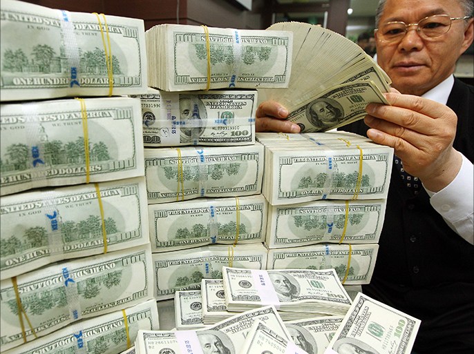 epa01919188 An employee at Korea Exchange Bank stacks American dollars at the bank's head office in Seoul on 03 November 2009. The Bank of Korea said the same day the country's foreign exchange reserves reached their second-highest level ever in October as a weaker U.S. dollar