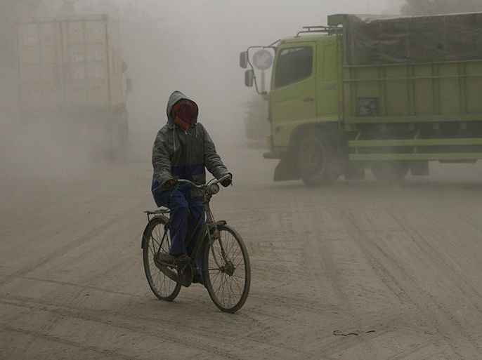 A man covers his face while riding a bicycle on a road covered with ash from Mount Kelud in Solo February 14, 2014. Mount Kelud volcano erupted late on Thursday night on the heavily populated Indonesian island of Java, sending a huge plume of ash and sand 17 km (10 miles) into the air and forcing the closure of three airports. Mount Kelud is 140 km south of Indonesia's second biggest city Surabaya, a major industrial centre. The cloud from the eruption was seen as far as 9 km to the west, and forced the shutdown of airports at Surabaya and the cities of Yogyakarta and Solo. REUTERS/Stringer (INDONESIA - Tags: DISASTER ENVIRONMENT)
