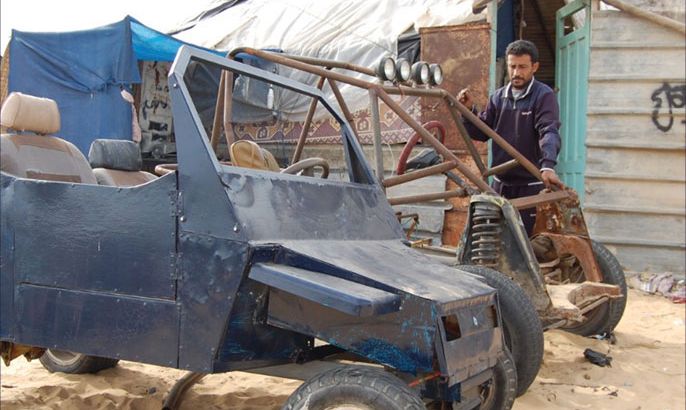 مروان ابو ستة يقف الى جانب مركبتين يعمل على تصنيعها واحدة لأحد الاحتياجات الخاصة والأخرى للسباق.