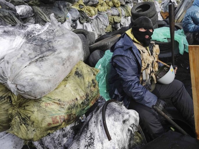 An anti-government protester sits a barricade at the site of recent clashes with riot police in Kiev February 17, 2014. Ukraine's opposition leaders on Monday pressed President Viktor Yanukovich to accept curbs on his presidential powers that would allow them to form an independent government to defuse a 12-week stand-off on the streets and save the economy from collapse. REUTERS/Konstantin Chernichkin (UKRAINE - Tags: POLITICS CIVIL UNREST)