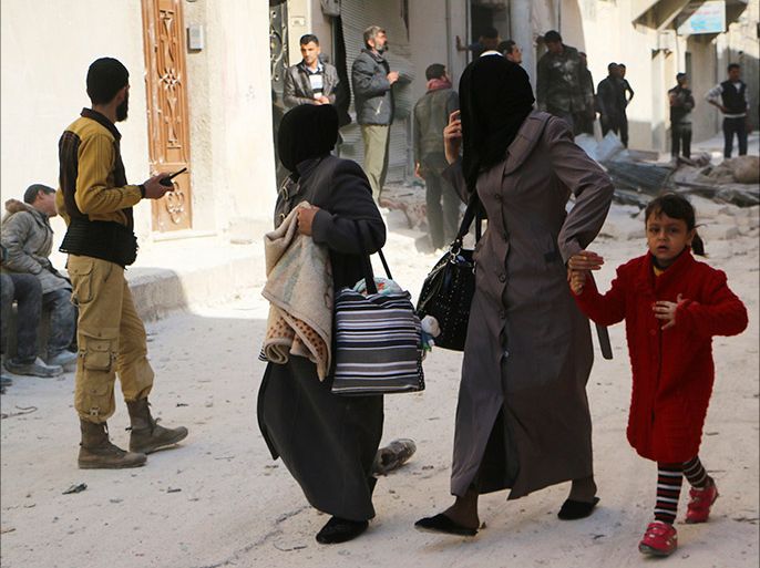 Women walk at a damaged site after what activists said was an air strike by forces loyal to Syria's President Bashar al-Assad in Masaken Hanano in Aleppo February 14, 2014. REUTERS/Hosam Katan (SYRIA - Tags: POLITICS CIVIL UNREST CONFLICT)