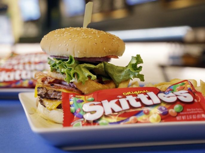 A "Beast Burger" that debuted earlier, in honor of running back Marshawn Lynch, is shown at an event debuting new Seattle Seahawks' team-themed menu items in a restaurant at the team's stadium Wednesday, Jan. 15, 2014, in Seattle. Food and beverage concessionaire Delaware North Sportservice displayed the menu items that will be served at the NFC football championship game Sunday, when the Seahawks host the San Francisco 49ers. Among the new fare is a 12-layer cake, over-sized cookies and crispy treats, a quarterback-inspired "DangeRuss Dog" and blue and green crusted corn dogs. The "Beast Burger," which debuted at the team's divisional playoff game against the New Orleans Saints, includes two burger patties, bacon, ham, cheese, onion rings and is served with fries and Skittles candy. (AP Photo/Elaine Thompson)