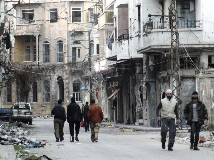 Men walk by damaged buildings in the besieged area of Homs February 24, 2014. Picture taken February 24, 2014. REUTERS/Yazan Homsy (SYRIA - Tags: POLITICS CIVIL UNREST CONFLICT)