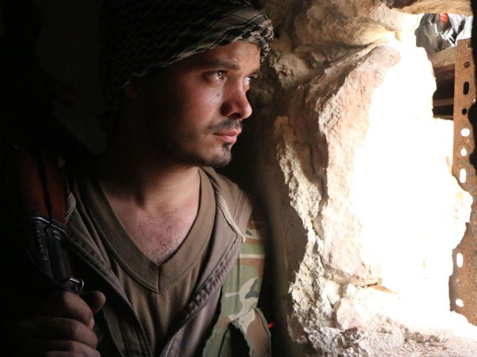 FH05 - Aleppo, -, SYRIA : A rebel fighter looks through a hole in the wall as he