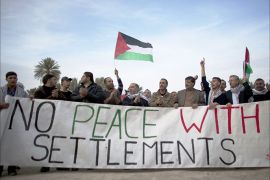 Palestinians and Israeli activists hold a banner reading "No peace with settlements" as they take part in a protest denouncing the repeated refusals of the Israeli Prime Minister to dismantle Jewish settlements, on January 31, 2014