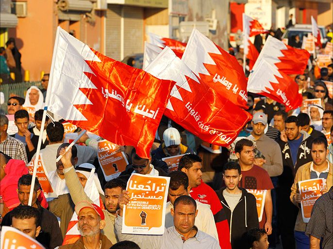Anti-government protesters holding Bahraini flags and signs that read "It Is Impossible For The Bahraini People To Give up On Democracy" march during an anti-government rally in the village of Bilad al-Qadeem south of Manama, February