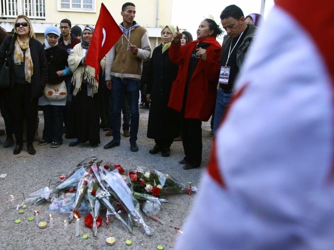 People gather in front of flowers and candles to mourn the first anniversary of the assassination of Tunisian opposition leader Chokri Belaid, outside his flat in Tunis February 6, 2014. REUTERS/Anis Mili (TUNISIA - Tags: POLITICS ANNIVERSARY)