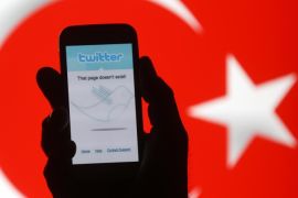 A holds holds a Samsung Galaxy S4 displaying a Twitter error message in front of Turkish national flag in this illustration taken in Zenica, March 21, 2014. Turkey's courts have blocked access to Twitter a little over a week before elections as Prime Minister Tayyip Erdogan battles a corruption scandal that has seen social media awash with alleged evidence of government wrongdoing. The ban came hours after a defiant Erdogan, on the campaign trail ahead of key March 30 local elections, vowed to "wipe out" Twitter and said he did not care what the international community had to say about it. REUTERS/Dado Ruvic (BOSNIA AND HERZEGOVINA - Tags: POLITICS)