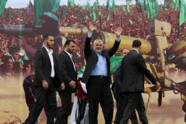 Gaza's Hamas Prime Minister Ismail Haniyeh, center, waves to the crowd from a stage during a rally of tens of thousands of Hamas supporters to commemorate the 10-year anniversary of the assassination of the group's spiritual leader Sheik Ahmed Yassin in an Israeli airstrike a decade ago, in Gaza City, Sunday, March 23, 2014. The Islamic militant group's top leadership was on hand for Sunday's rally, and thousands of people holding Hamas flags and wearing Hamas bandanas have turned downtown Gaza City into a sea of green. (AP Photo/Hatem Moussa)