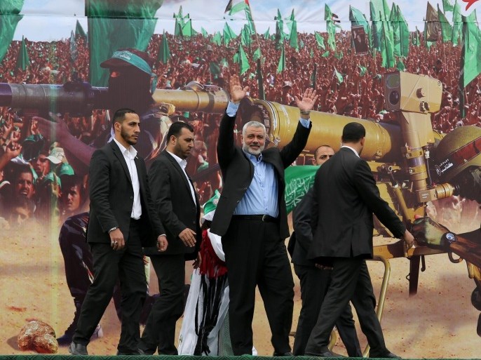 Gaza's Hamas Prime Minister Ismail Haniyeh, center, waves to the crowd from a stage during a rally of tens of thousands of Hamas supporters to commemorate the 10-year anniversary of the assassination of the group's spiritual leader Sheik Ahmed Yassin in an Israeli airstrike a decade ago, in Gaza City, Sunday, March 23, 2014. The Islamic militant group's top leadership was on hand for Sunday's rally, and thousands of people holding Hamas flags and wearing Hamas bandanas have turned downtown Gaza City into a sea of green. (AP Photo/Hatem Moussa)
