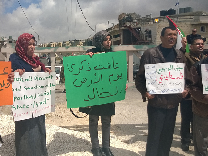 ‪فلسطينيون بمنطقة الرأس بالخليل يحملون لافتات إحياء لذكرى يوم الأرض‬ (الجزيرة)