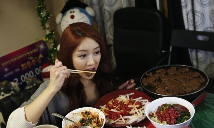 Park Seo-yeon, 34, eats in front of a video camera during her eating show in her apartment in Incheon, west of Seoul January 22, 2014. Known as The Diva, Park broadcasts for up to three hours every day from her apartment, where she eats alone as thousands of viewers watch and chat with her in real time over the Internet. South Korea's latest fad - gastronomic voyeurism - offers surprising amounts of money to thousands of online diners while serving up a sense of community in the wealthy Asian country's increasingly solitary society. To match story KOREA-EATING/ONLINE Picture taken January 22, 2014. REUTERS/Kim Hong-Ji (SOUTH KOREA - Tags: SOCIETY SCIENCE TECHNOLOGY FOOD)