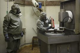 (FILES) This photo taken on October 30, 2013, shows employees in protective gear preparing to dismantle a dummy grenade during a demonstration at a chemical weapons disposal facility of GEKA (Gesellschaft zur Entsorgung von chemischen Kampfstoffen und Ruestungsaltlasten) in Munster, northern Germany. Syria has surrendered or destroyed nearly a third of its chemical arsenal but remains behind on its international obligations, the head of the disarmament mission told the world's chemical watchdog on March 4, 2014. Syria has already missed several target dates to hand over or destroy its arsenal before a June 30 deadline and the United Nations-Organisation for the Prohibition of Chemical Weapons (OPCW) mission called on Damascus to move faster. AFP PHOTO / PHILIPP GUELLAND