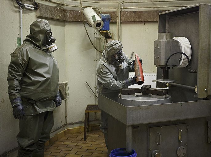 (FILES) This photo taken on October 30, 2013, shows employees in protective gear preparing to dismantle a dummy grenade during a demonstration at a chemical weapons disposal facility of GEKA (Gesellschaft zur Entsorgung von chemischen Kampfstoffen und Ruestungsaltlasten) in Munster, northern Germany. Syria has surrendered or destroyed nearly a third of its chemical arsenal but remains behind on its international obligations, the head of the disarmament mission told the world's chemical watchdog on March 4, 2014. Syria has already missed several target dates to hand over or destroy its arsenal before a June 30 deadline and the United Nations-Organisation for the Prohibition of Chemical Weapons (OPCW) mission called on Damascus to move faster. AFP PHOTO / PHILIPP GUELLAND