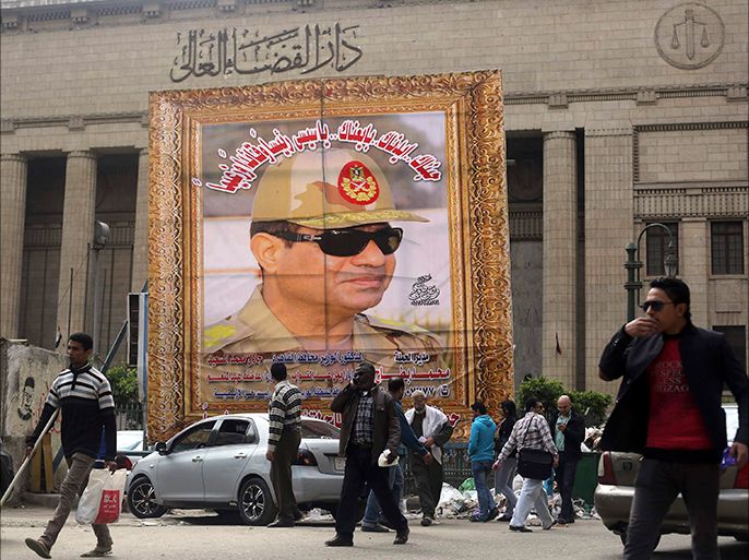 People walk past a huge banner for Egypt's army chief, Field Marshal Abdel Fattah al-Sisi in front of the High Court of Justice in downtown Cairo, March 13, 2014. Cairo's souvenir shops and street stands are filled with memorabilia celebrating al-Sisi. Egypt is pushing ahead with an army-backed plan for political transition, with presidential and parliamentary elections due to take place within months. Sisi is widely expected to announce his presidential bid and win easily. Poster reads, "We love and support you. You are our president and leader". REUTERS/Amr Abdallah Dalsh (EGYPT - Tags: POLITICS MILITARY ELECTIONS)