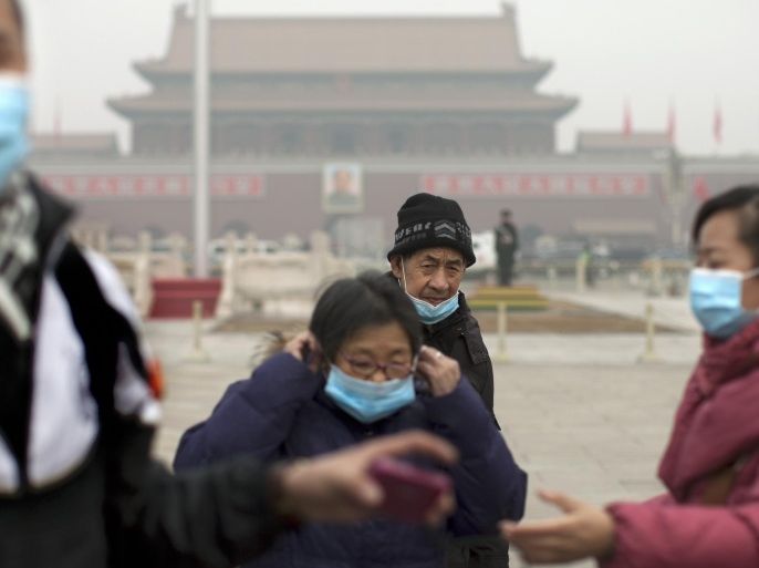 FILE - In this Tuesday, Feb. 25, 2014 file photo, tourists put on their masks after posing for photos as they visit Tiananmen Square on a severely polluted day in Beijing, China. Air pollution kills about 7 million people worldwide every year according to a new report from the World Health Organization published Tuesday, March 25, 2014. The agency said air pollution triggers about 1 in 8 deaths and has now become the single biggest environmental health risk, ahead of other dangers like second-hand smoke. (AP Photo/Alexander F. Yuan, File)