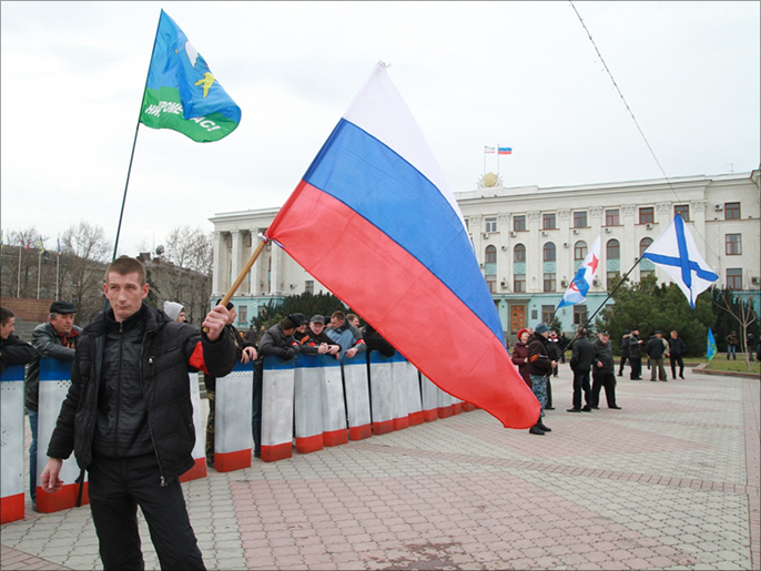 ‪‬ ماكسيم ملوحا بالعلم الروسي أمام مبنى حكومة الإقليم(الجزيرة نت)