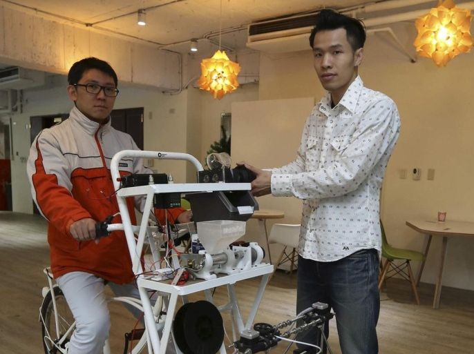 Kamm Kai-yu (R), a co-founder of boutique design studio Fabraft, displays a bicycle with a 3D printer installed in front, in Taipei March 13, 2014. Cycling through the streets of Taiwan's capital, staff from the design company turn discarded plastic cups and bottles into pieces of art on the spot with Mobile Fab - an ordinary bike kitted out with a computer and 3D printer. Picture taken March 13. To match story TAIWAN-3D/ REUTERS/Patrick Lin (TAIWAN - Tags: SCIENCE TECHNOLOGY SOCIETY)