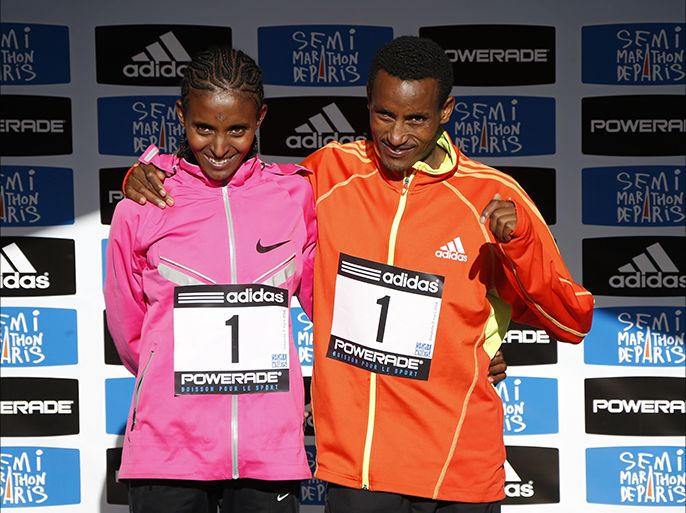 Ethiopian athletes Yebrgual Melese (L) and Mulle Wasihun pose on the podium after winning the 22nd edition of the Paris Half-Marathon (21.1 km), respectively in the women's and the men's category, on March 2, 2014 in Paris. Melese