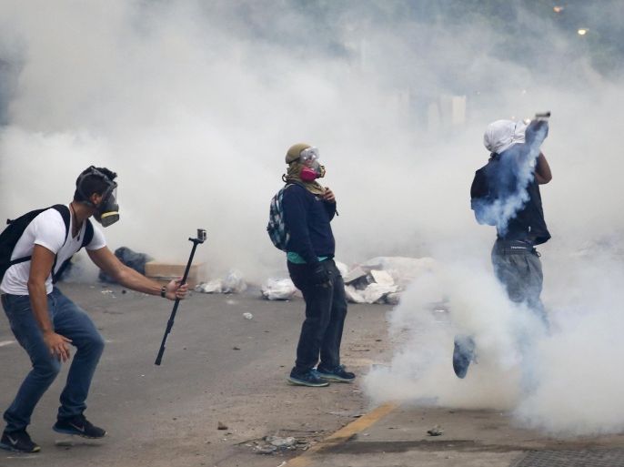 An anti-government protester films another protester throwing a gas canister back at police during a protest against President Nicolas Maduro's government in Caracas March 7, 2014. Latin American foreign ministers will meet next week to discuss the unrest in Venezuela that has left at least 20 dead and convulsed the South American OPEC nation, diplomatic sources said on Friday. REUTERS/Carlos Garcia Rawlins (VENEZUELA - Tags: POLITICS CIVIL UNREST)