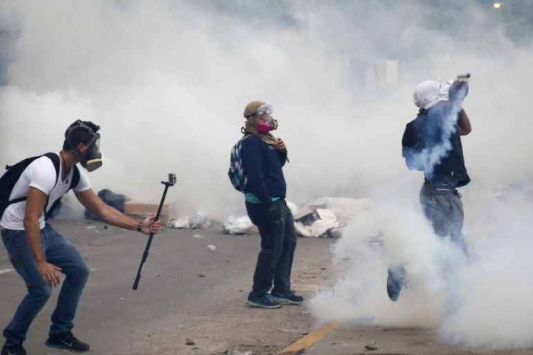 An anti-government protester films another protester throwing a gas canister back at police during a protest against President Nicolas Maduro's government in Caracas March 7, 2014. Latin American foreign ministers will meet next week to discuss the unrest in Venezuela that has left at least 20 dead and convulsed the South American OPEC nation, diplomatic sources said on Friday. REUTERS/Carlos Garcia Rawlins (VENEZUELA - Tags: POLITICS CIVIL UNREST)