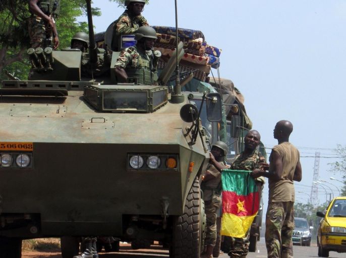 A Cameroonian soldier of the African-led International Support Mission to the Central African Republic (MISCA) holds a Cameroonian flag next to an armoured vehicle as the soldiers patrol in the PK5 district of Bangui after an attack by anti-Balaka Christian militiamen on March 22, 2014. The UN's rights chief on March 20 expressed horror at the level of violence in the Central African Republic, citing cannibalism, child decapitations and gruesome lynchings. The chronically unstable country sank into chaos when rebels who had helped topple president Francois Bozize a year ago went rogue. The ensuing campaign of killing, raping and looting by the mainly Muslim former rebels prompted members of the Christian majority to form vigilantes known as 'anti-balaka' (anti-machete). AFP PHOTO / PACOME PABANDJI
