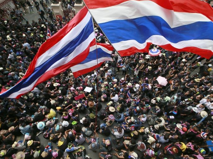 Anti-government protesters wave national flags at the gates of the police headquarters during a memorial for the children killed in recent bomb blasts in Bangkok, Thailand, Wednesday, Feb. 26, 2014. Violence spread Tuesday to another anti-government protest site in Thailand's capital following weekend explosions that left five people dead, including four children, security officials said. (AP Photo/Wason Wanichakorn)
