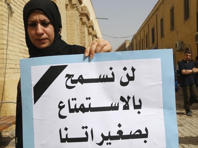 An Iraqi woman holds a sign during a demonstration against the draft of the "Al Ja'afari" Personal Status Law in Baghdad March 7, 2014. About two dozen Iraqi women demonstrated on March 8, 2014 in Baghdad against a draft law approved by the Iraqi cabinet that would permit the marriage of nine-year-old girls and automatically give child custody to fathers. The sign reads," We do not allow you to have joy with our minors". Picture taken March 7, 2014. REUTERS/Thaier al-Sudani (IRAQ - Tags: SOCIETY ANNIVERSARY POLITICS CIVIL UNREST)