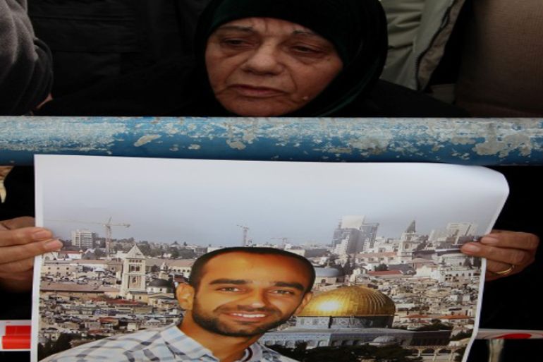 أم رأفت وهي تمسك بلافتة تطالب بإطلاق سراح ابنها سامر ايام اعتقاله