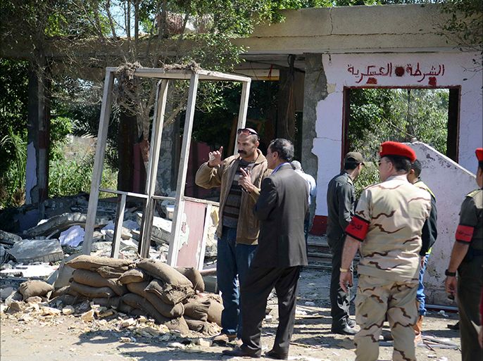 Egyptian soldiers and officials inspect the sight where gunmen killed six soldiers at a Cairo checkpoint on March 15, 2014 in an attack the military blamed on the Muslim Brotherhood movement of deposed president Mohamed Morsi. The attack came two days after gunmen killed a soldier in Cairo, as militants once