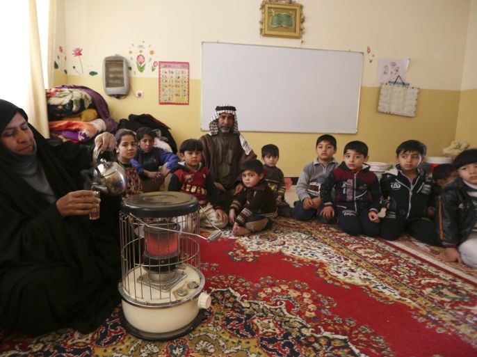 A woman pours tea near others, who fled violence in the western Iraqi city of Falluja, sitting inside a classroom at a school being used as a shelter for internally-displaced persons in Samarra, some 100 km (62 miles) north of Baghdad, February 2, 2014. Thousands of families have fled Falluja, as Iraqi government forces battling al Qaeda-linked militants intensified airstrikes and artillery fire on the rebel-held city. Picture taken February 2, 2014. REUTERS/Bakr al-Azzawi (IRAQ - Tags: CIVIL UNREST POLITICS CONFLICT)