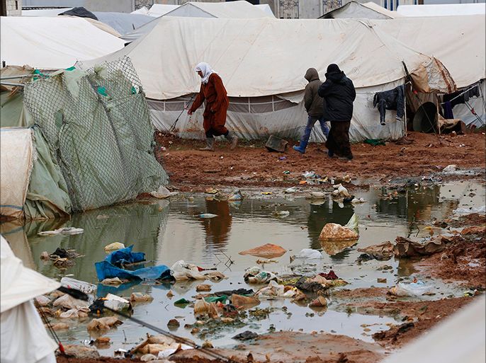 Syrian refugees walk near a puddle of rain outside tents at the Bab Al-Salam refugee camp in Azaz, near the Syrian-Turkish border, March 14, 2014. REUTERS/Hamid Khatib (SYRIA - Tags: CIVIL UNREST POLITICS CONFLICT ENVIRONMENT)