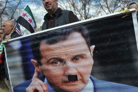 A man holds a poster of President Bashar al-Assad with a Hitler moustache over it during a rally against the Syrian government on March 15, 2014 at Lafayette Square, across from the White House, in Washington to mark the third anniversary of the start of the conflict in Syria. The unrest began on March 15, 2011 after popular uprisings that toppled dictators in Tunisia and Egypt and has turned into a full-blown civil war, leaving over 100,000 people dead and forcing some 9 million people from their homes. AFP PHOTO/Mandel NGAN