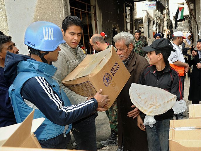 epa04132543 A handout photo released by Syria's official state news agency Syrian Arab News Agency (SANA) shows members of the United Nations Relief and Works Agency (UNRWA) distributing food parcels to residents of al-Yarmouk refugee Palestinian camp in Damascus, Syria, 18 March 2014. According to SANA the distribution of food aid, polio vaccines and milk in Yarmouk Camp in Damascus and the evacuation of humanitarian cases was resumed on 18 March