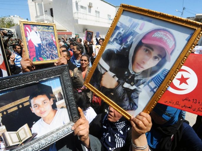 Family members of those killed during the 2011 Tunisian Revolution (portrait), shout slogans during a gathering on April 16, 2014, in front to National Constituent Assembly in the capital Tunis to protest against lenient verdicts by a military court against former officials of the regime of Ben Ali in the case of protesters killed and injured during the revolution. AFP PHOTO / FETHI BELAID