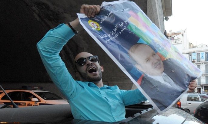 A supporter of President Abdelaziz Bouteflika displays his portrait to celebrate in Algiers, Algeria, on Friday, April 18, 2014, the announcement of his landslide re-election victory. President Abdelaziz Bouteflika, who had a stroke last year, won a staggering 81 percent of the vote in Thursday's election despite not even appearing in his own campaign. (AP Photo/Sidali Djarboub )