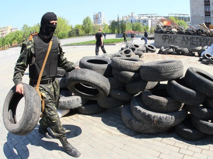 Masked pro-Russian activists reinforce their barricade outside the regional state building seized by the separatists in eastern Ukrainian city of Donetsk on April 26, 2014. Pro-Russian rebels holding a group of international OSCE observers in eastern Ukraine on Saturday accused them of being 'NATO spies' and vowed to continue detaining them. AFP PHOTO/ ALEXANDER KHUDOTEPLY