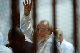 Leader of Egypt's Muslim Brotherhood Mohammed Badie sits inside a defendants cage as he raises his four fingers, a Rabaah al-Adawiya mosque symbol, where ousted leader Mohammed Morsi supporters had held a sit-in for weeks that was violently dispersed in August, during his trial in Cairo, Egypt, Wednesday, April 30, 2014. (AP Photo/Ahmed Omar) EGYPT OUT