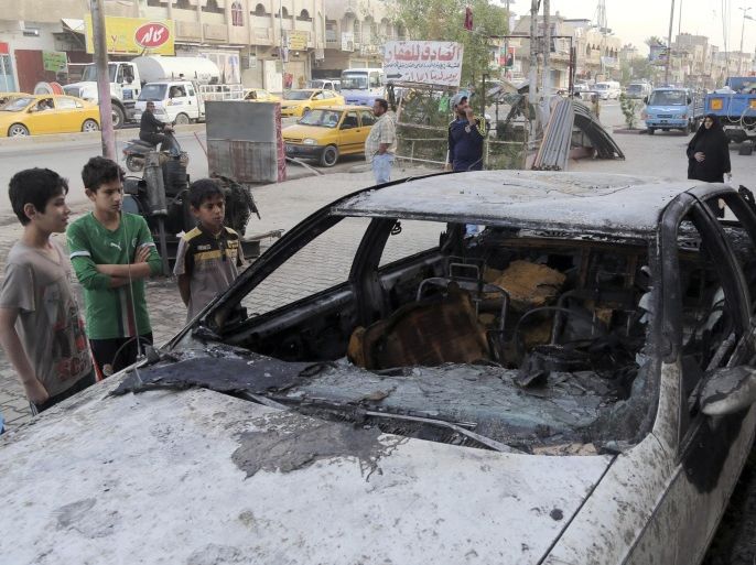 Civilians inspect a damaged vehicle in the aftermath of a Monday car bomb attack in a crowded commercial street in Baghdad's eastern neighborhood of Sadr City, Iraq, Tuesday, April 22, 2014. Suicide bombings and other attacks across Iraq killed and wounded dozens on Monday, officials said, the latest in an uptick in violence as the country counts down to crucial parliamentary elections later this month. (AP Photo/Karim Kadim)