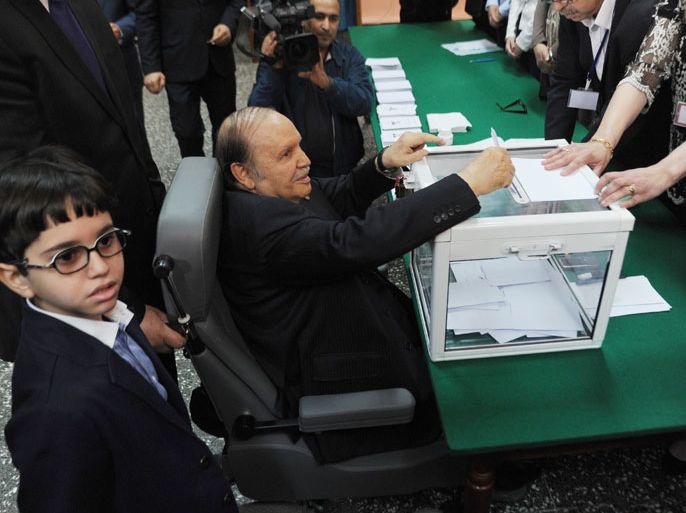 Algeria's ailing President Abdelaziz Bouteflika (C), running for re-election, casts his ballot from a wheelchair as his nephew (L) watches on at a polling station in Algiers on April 17, 2014. Algerians were voting in presidential elections, with Bouteflika widely expected to win a fourth term despite chronic health problems, fraud warnings and calls for a boycott. AFP PHOTO / FAROUK BATICHE