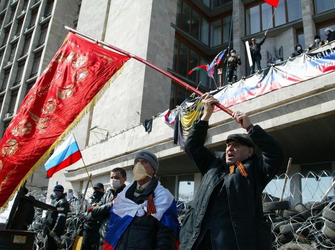 Activists wave an old Soviet and Russian national flags in front of a barricade at the regional administration building, in Donetsk, Ukraine, Monday, April 7, 2014. A Ukrainian news agency is reporting that pro-Russian separatists who have seized the regional administration building in the eastern Ukrainian city of Donetsk proclaimed the region an independent republic. The activists on Monday also called for a referendum on the sovereignty of the Donetsk region, which borders Russia, to be held no later than May 11, the Interfax news agency reported. (AP Photo/Alexander Ermochenko)