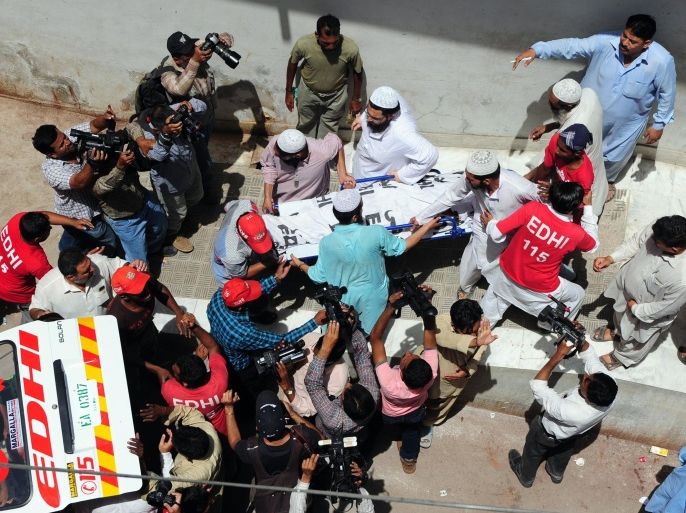 Pakistani religious students and volunteers carry the body of a blast victim at a hospital in Karachi on April 28, 2014. A blast killed three boys aged between 10 and 12 at a religious seminary in the southern Pakistani city of Karachi, police said. AFP PHOTO/ASIF HASSAN