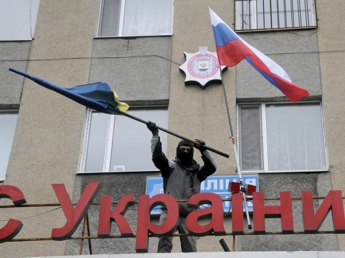 A masked pro-Russian man discards a Ukrainian flag after replacing it with a Russian flag on a ledge above a police station stormed by a mob in Horlivka, eastern Ukraine, Monday, April 14, 2014. The text reads: "Ukrainian police station in Horlivka". Ukraine's acting President Oleksandr Turchynov on Monday called for the deployment of United Nations peacekeeping troops in the east of the country, where pro-Russian insurgents have occupied buildings in nearly 10 cities. (AP Photo/Efrem Lukatsky)