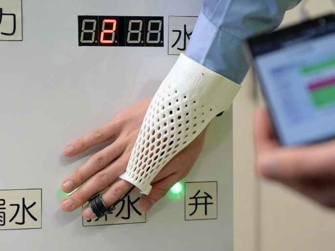 A Fujitsu employee demonstrates the company's new technology, glove-style wearable device which can read NFC tag to display the information onto a head mounted display and input six-keys, (up, down, left, right, clock-wise and anti-clock-wise truns) using gestures during its press preview in Tokyo on February 18, 2014. The device can display information such as the operation manuals as well as input operation logs without distabing operation steps. AFP PHOTO / TOSHIFUMI KITAMURA