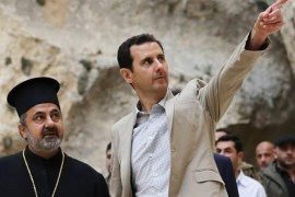 In this photo taken on Sunday April 20, 2014 and released by the Syrian official news agency SANA, Syrian President Bashar Assad, right, visits the Christian village of Maaloula, near Damascus, Syria. Assad visited on Sunday a historic Christian village his forces recently captured from rebels, state media said, as the country's Greek Orthodox Patriarch vowed that Christians in the war-ravaged country "will not submit and yield" to extremists. The rebels, including fighters from the al-Qaida-affiliated Nusra Front, took Maaloula several times late last year. (AP Photo/SANA)