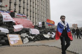 A pro-Russian activist with a Russian flag pass by a barricade at a regional administration building that they had seized earlier in Donetsk, Ukraine, in Donetsk, Ukraine, Friday, April 11, 2014. Ukraine’s prime minister on Friday told leaders in the country’s restive east that he is committed to allowing regions to have more powers. Yatsenyuk Friday morning flew into Donetsk, where pro-Russian separatists are occupying the regional administration building and calling for a referendum that could prefigure seeking annexation by Russia. (AP Photo/Efrem Lukatsky)